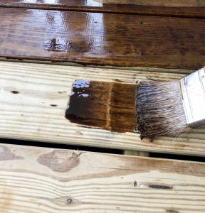 Staining wood porch or deck with stain water sealing for rain and snow and harsh sun